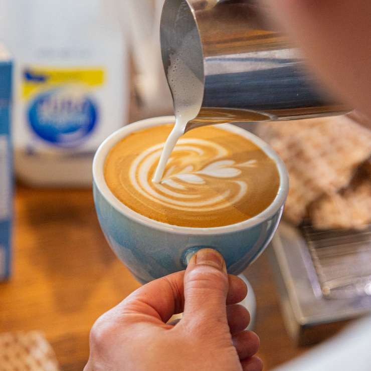 Pouring latte art onto a coffee